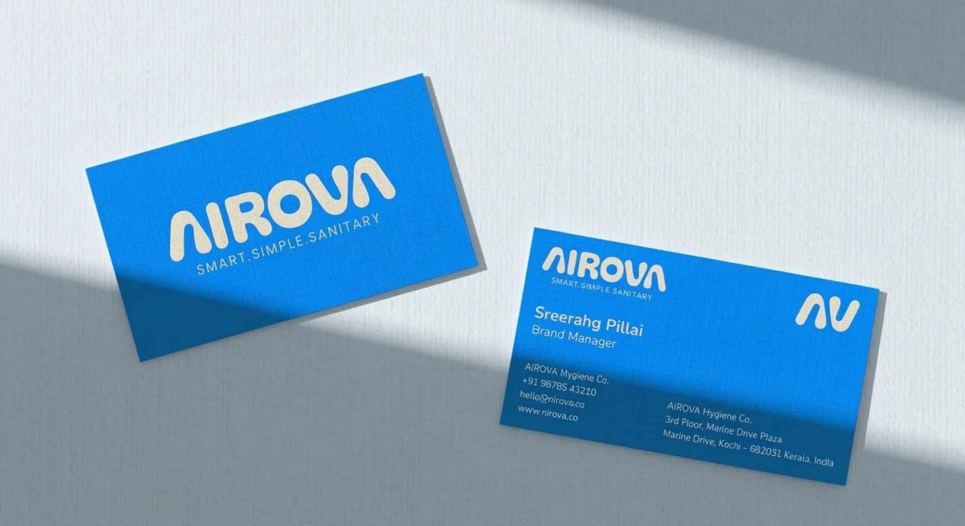 Two Airova business cards on a pale surface under raking light, front and back
